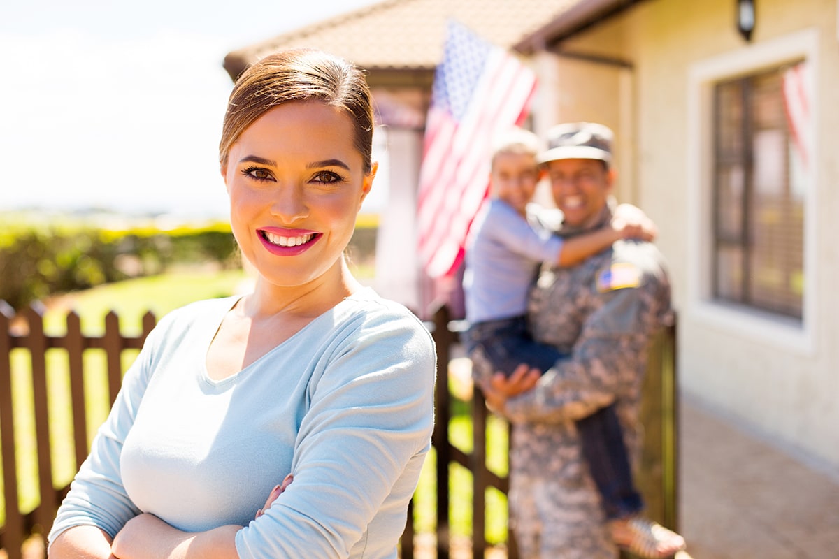 image of a veteran standing in front of her new home with her family